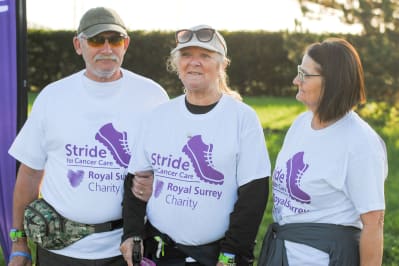 Image shows a man and two women wearing a t-shirt which reads: Stride for Cancer Care and Royal Surrey Charity.