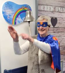 Evelyn Stone wearing a superhero costume ringing the bell at St Lukes.